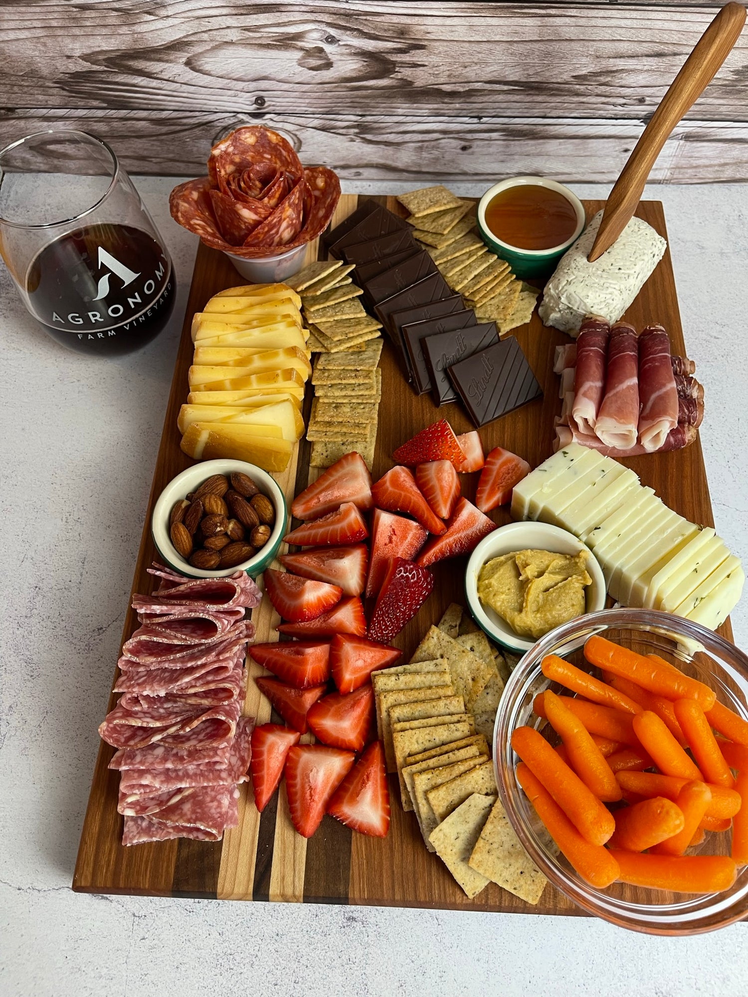A colorful charcuterie board, covered in chopped fruit, deli meats, cheese and dips