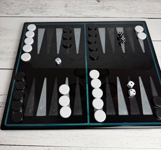 Handcrafted black resin backgammon board with teal epoxy border, gray points, black and white checkers, and dice — Bees Boards