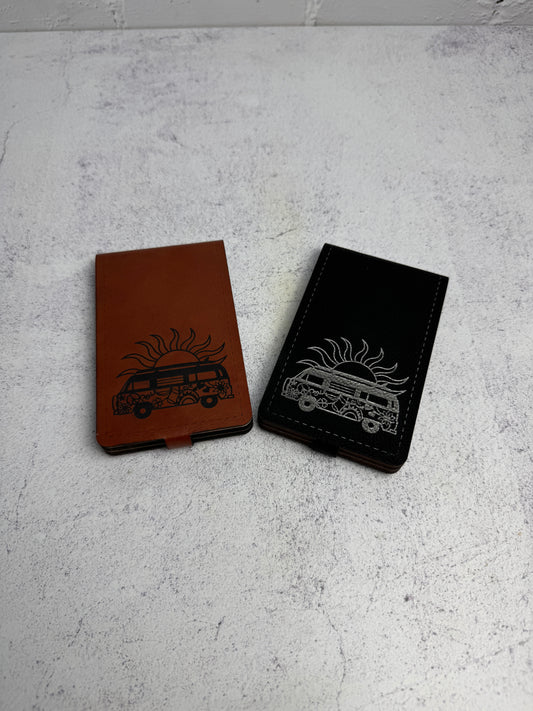 Black and brown leatherette folding cribbage boards with retro bus designs on a gray surface